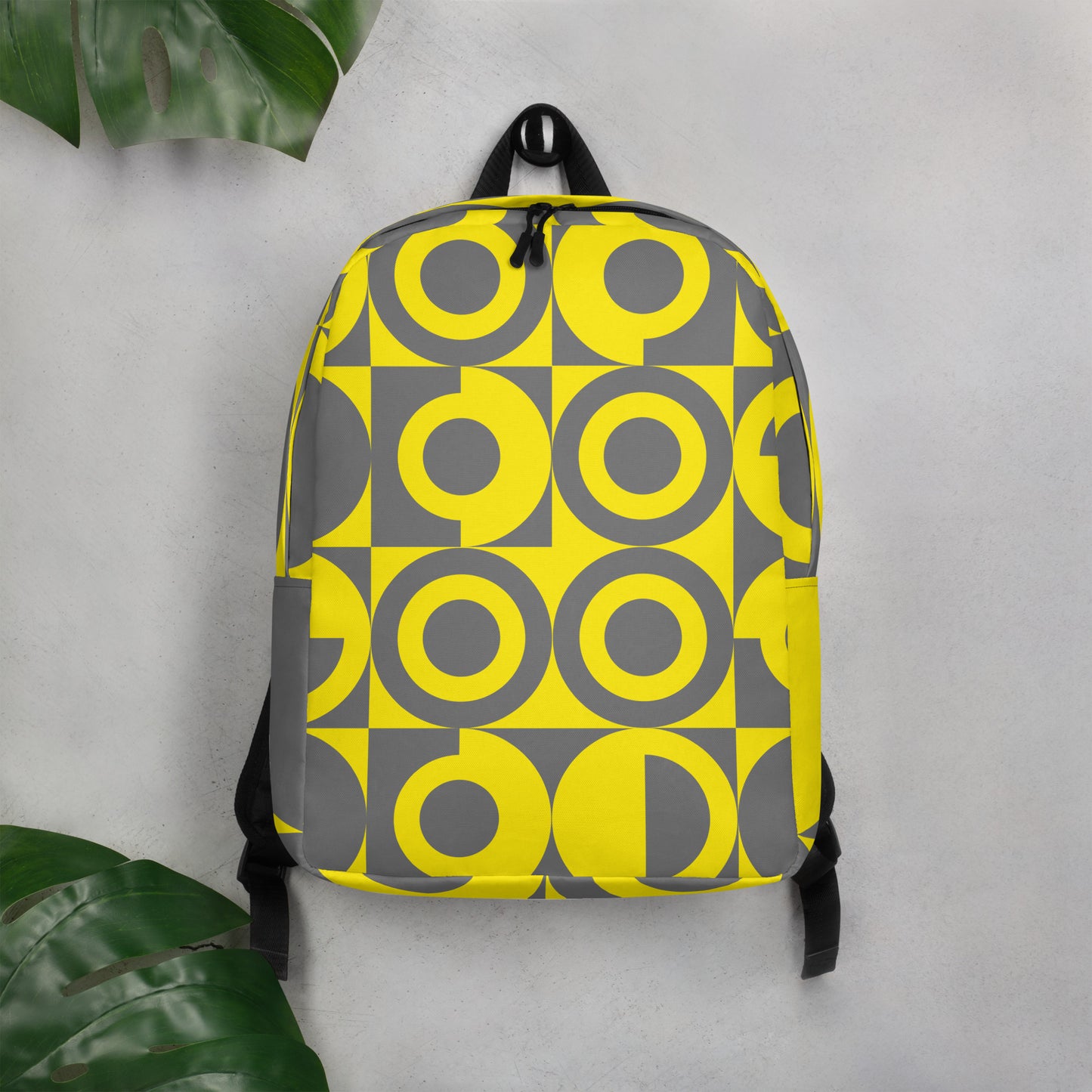 Yellow and Grey Geometric Pattern Backpack, front view with grey background hanging on a hook on the wall
