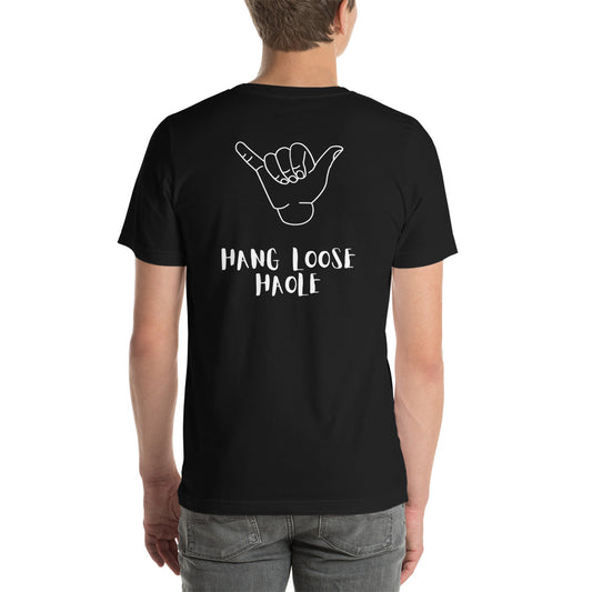 I speak in North Shore Movie Quotes in large text, Picture of a Movie Scene Marker with Surfer holding a surfboard on the beach short sleeve t-shirt in black with Hang Loose Haole in large text on the back with a large shaka hand
