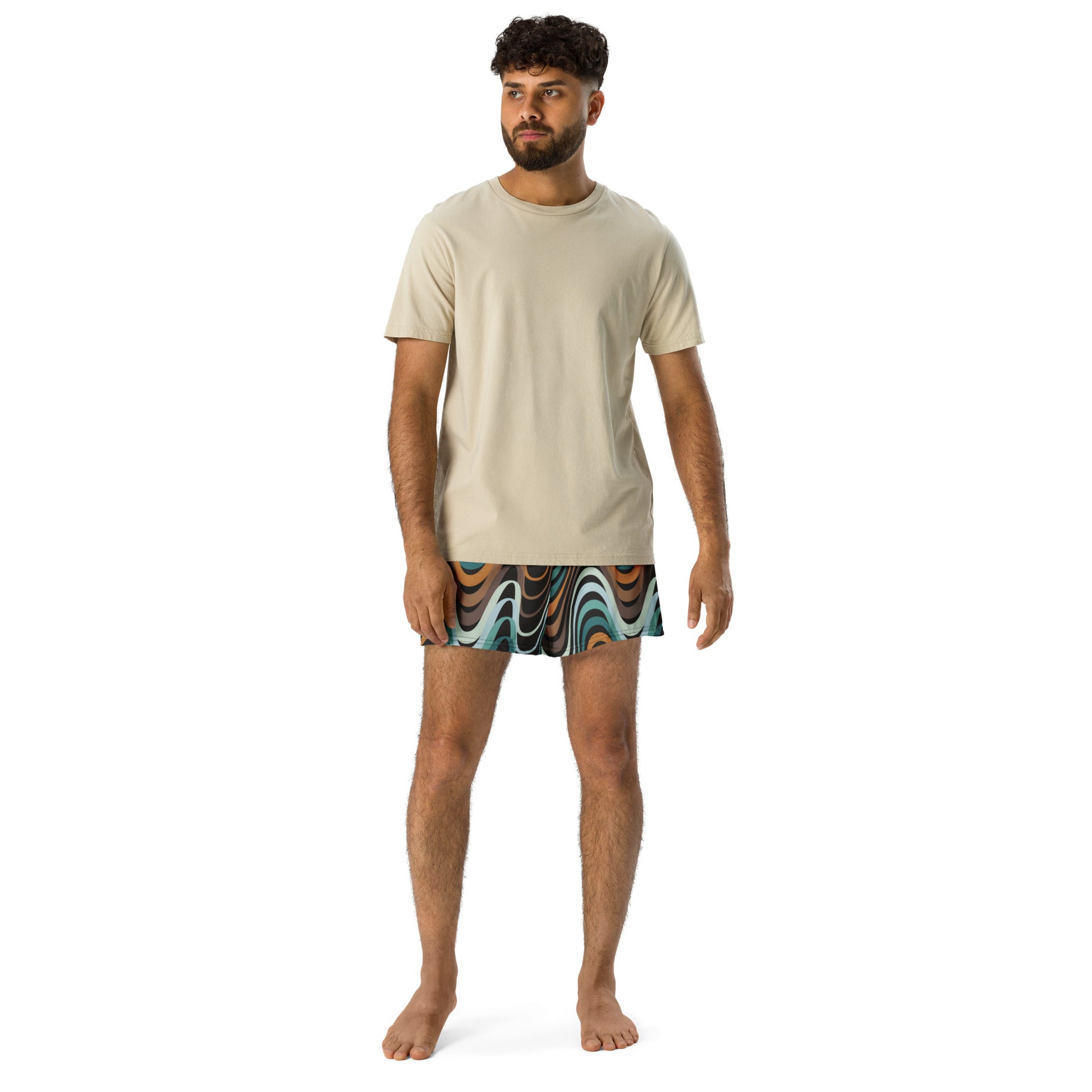 Man wearing a beige t-shirt and patterned shorts on a white background