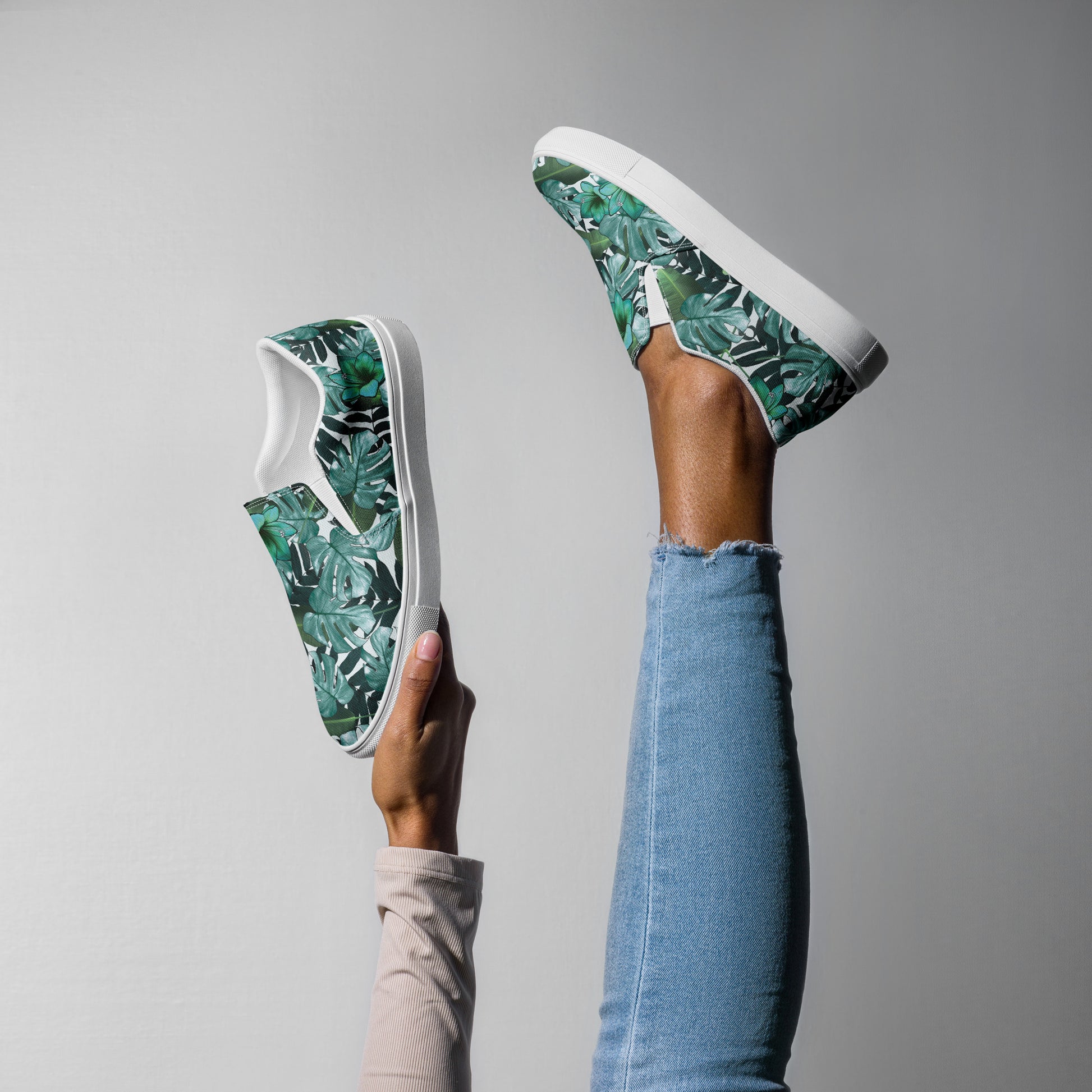 multicolor green tropical print canvas slip on shoes on a woman foot up in the air and one in hand top and side view