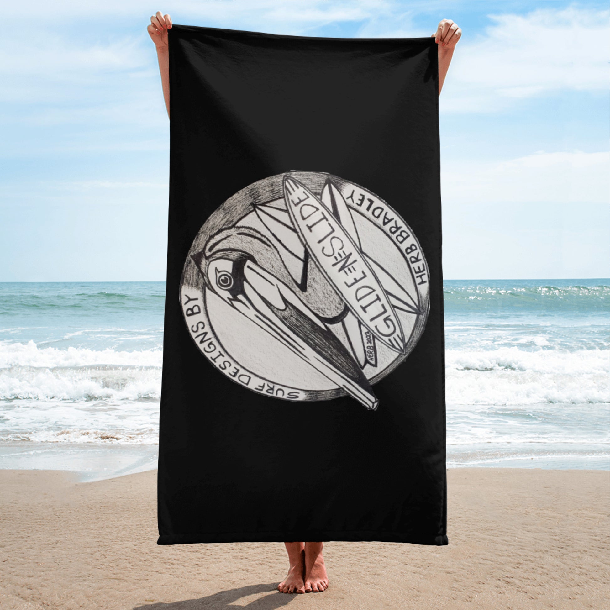 Black Glide -N- Slide Giant Beach Towel with black and grey logo being held up on the beach length wise