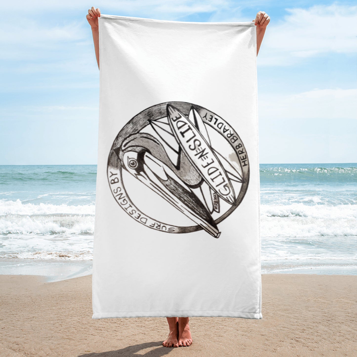 White Glide -N- Slide Giant Beach Towel with black and grey logo being held up on the beach length wise