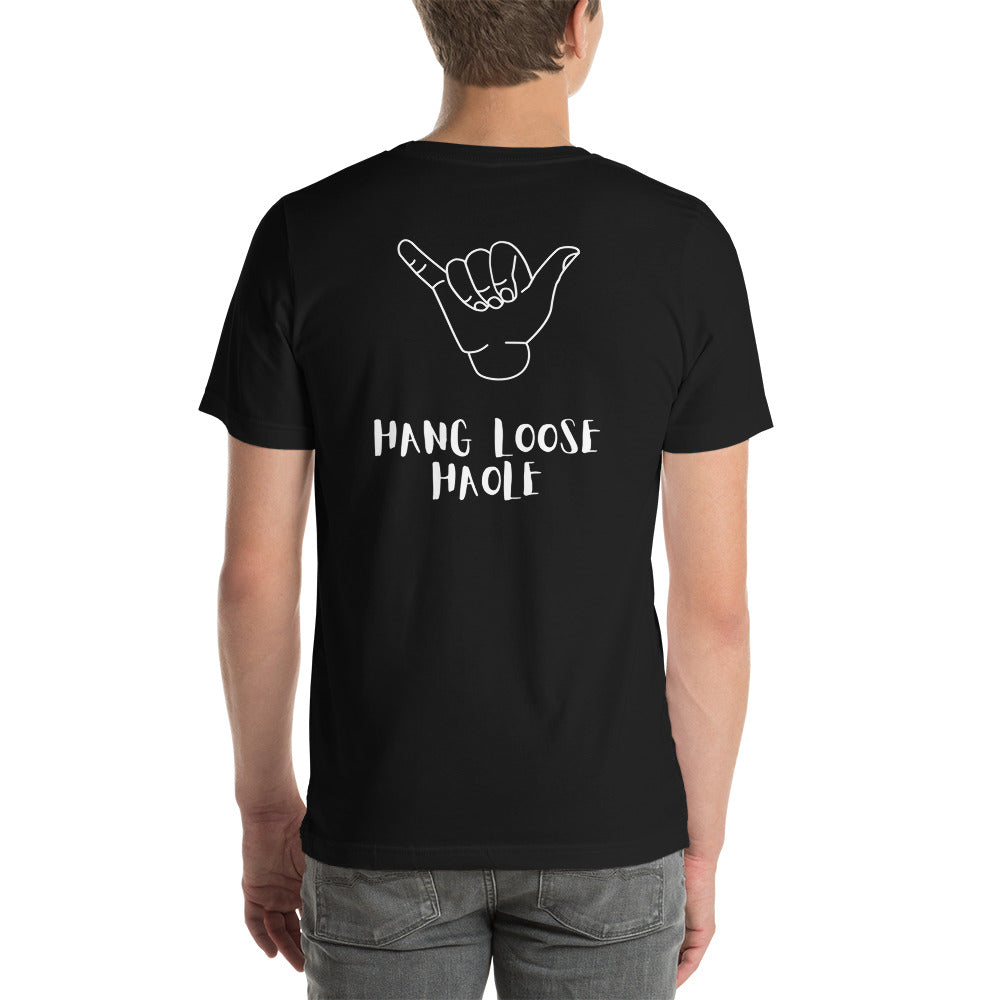 I speak in North Shore Movie Quotes in large text, Picture of a Movie Scene Marker with Surfer holding a surfboard on the beach short sleeve t-shirt in black with Hang Loose Haole in large text on the back with a large shaka hand